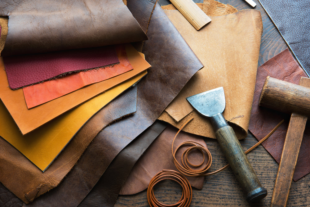 Leather craft or leather working. Selected pieces of beautifully colored or tanned leather on leather shoes craftman's work desk . 